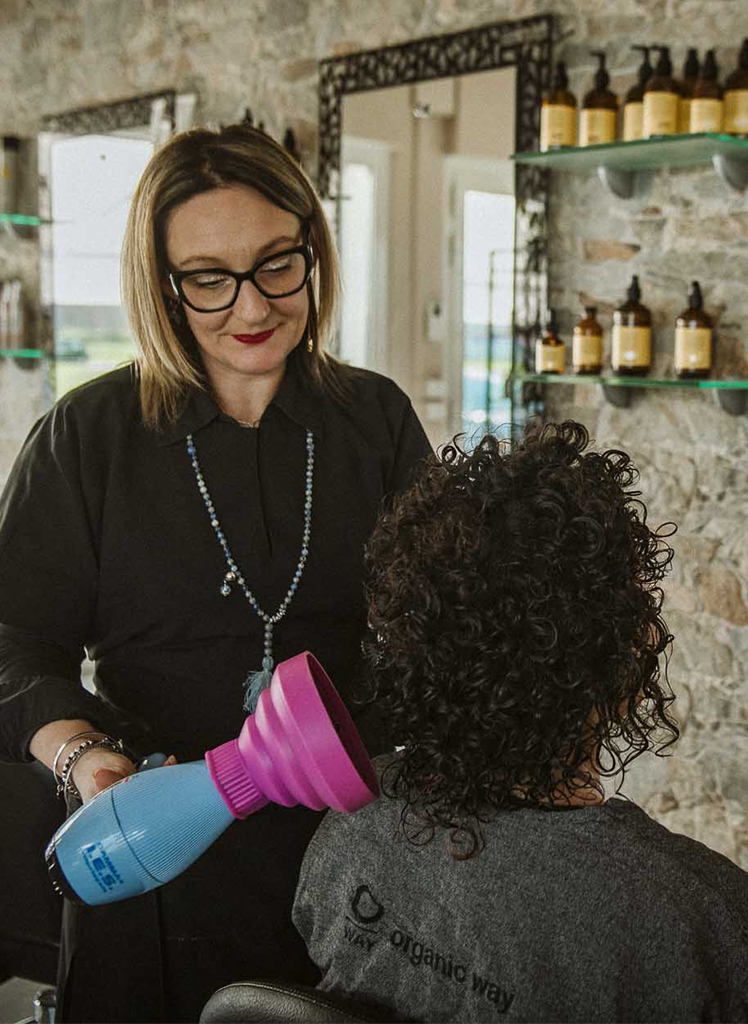 Parrucchiera mette in piega capelli ricci